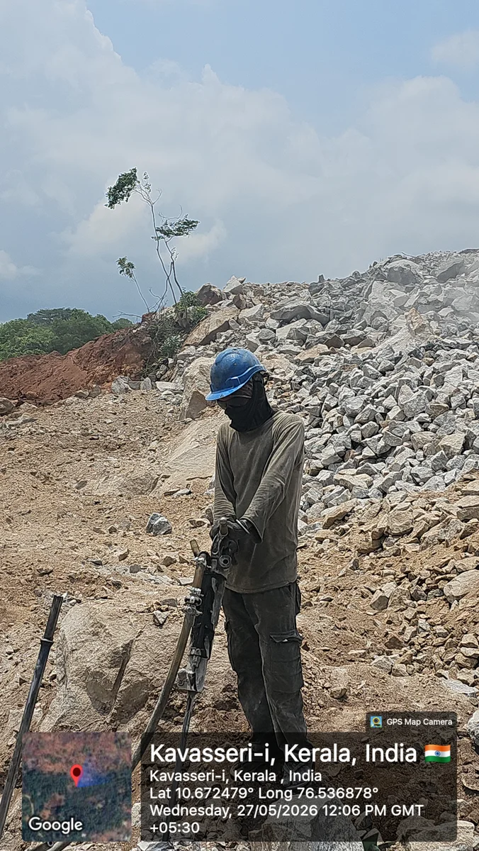 Quarry worker operating a heavy pneumatic jackhammer drill at the rock face